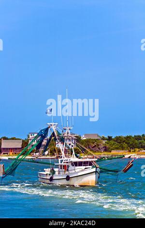 small fishing boat heading out to the ocean Stock Photo