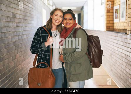 Campus besties. Portrait of two attractive young female university students standing in a campus corridor. Stock Photo