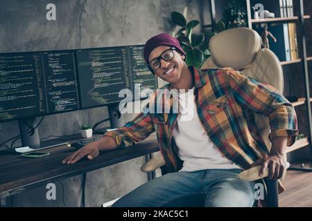 Photo of positive cheerful freelancer wear hat glasses working game developing indoors workplace workstation loft Stock Photo