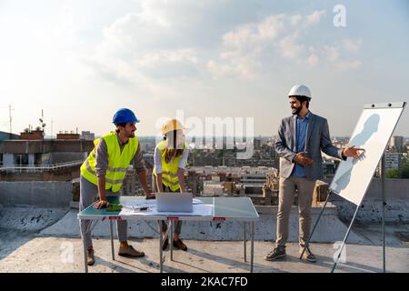 Construction concept. Engineers and architects working at construction site with blueprint Stock Photo