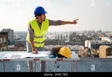 Young businessman construction site engineer working with architect blueprints on construction site. Stock Photo