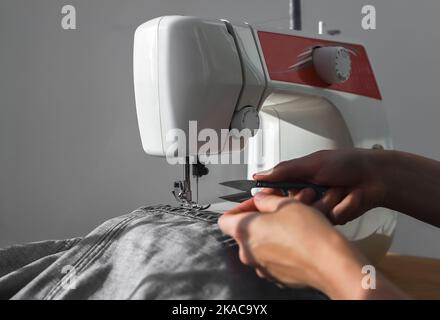 A needle and thread sew up a hole in a denim. Work of a seamstress or  tailor with a needle Stock Photo - Alamy