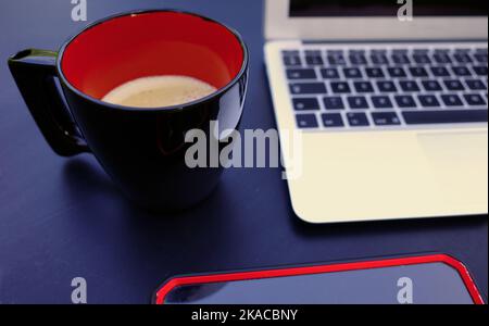 A working place with laptop, smartphone and black and red mug with coffee Stock Photo