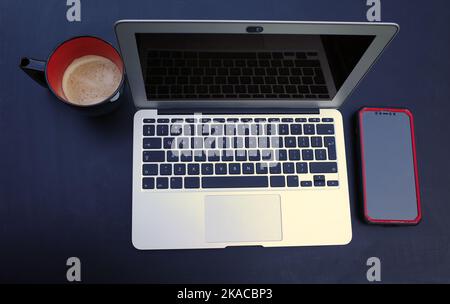 Top view on a working place with laptop, smartphone and black and red mug with coffee Stock Photo
