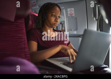This plane has onboard wifi. an attractive young woman using her laptop while sitting on a plane. Stock Photo