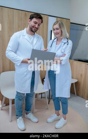 Joyous physicians in white lab coats standing in reception area Stock Photo