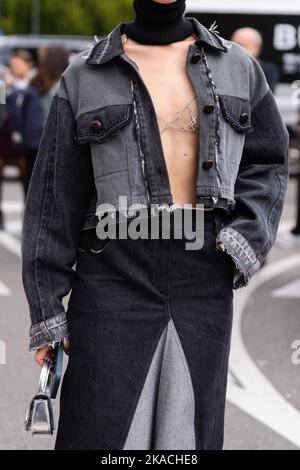 Milan, Italy - September, 21, 2022: woman wear black wool turtleneck, black and grey faded denim ripped jacket, long ripped skirt, silver shiny Stock Photo