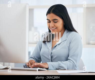 Business woman, computer and office work by happy, smile and relax employee working online project. Indian, designer and internet research for design Stock Photo