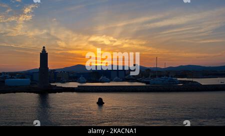 Orange sunset over Lighthouse on the approach to Pisa port Stock Photo