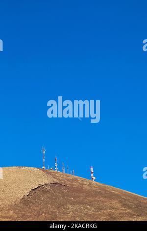 Radio telecommunications tower on top of an old volcano in Lanzarote, Spain with aircraft in the sky Stock Photo