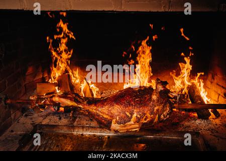 The lamb is cooked entirely on a spit on the fire. Cooking Stock Photo