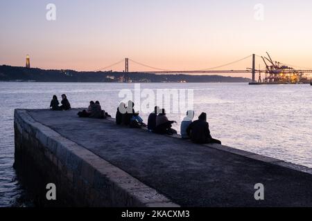 IDYLLIC EVENING: Sunset over Ponte 25 de Abril bridge and Santuário de Cristo Rei on the Tejo Promenade along River Tagus (Rio Tejo), Lisbon, Portugal Stock Photo