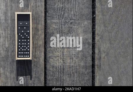Wooden box with domino game pieces on wood desk. Banner with copy space. Stock Photo