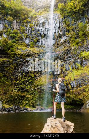 woman standing on the rock and looking to the Risco waterfall in Madeira island. Portugal Stock Photo