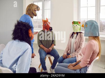 Conversation of young people in rubber masks on their heads during support group meeting. Stock Photo