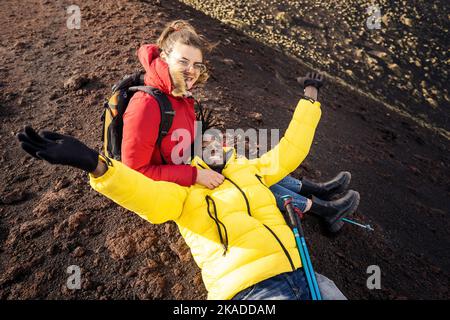 Couple of multiethnic hikers relaxing resting on the mountain peak posing for a picture looking at the camera - wanderlust people lifestyle concept Stock Photo