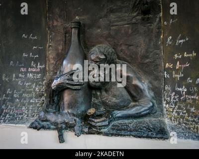 Vilnius, Lithuania - September 26, 2022: Bronze bas-relief of a drunkard with a big bottle of wine and a cat. Art on the wall of a house in Uzupis. Stock Photo