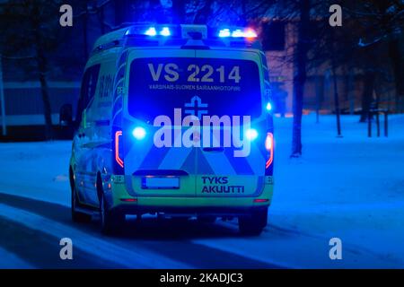 Mercedes-Benz ambulance on call on the street in the darkness of a winter night with blue lights flashing. Salo, Finland. December 28, 2021. Stock Photo