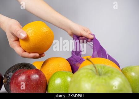A woman puts fruit in a net. The concept of abandoning plastic shopping bags Stock Photo