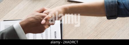 Top view of resume near job seeker and businessman shaking hands in office, banner,stock image Stock Photo