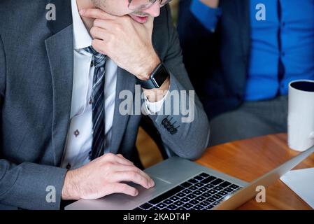 Young serious  professional business man, focused male student wearing glasses working on laptop Stock Photo