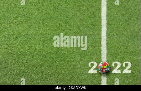 Top view detail of soccer field grass with ball with country flags on text 2022. Stock Photo