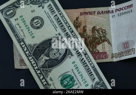 1 american dollar banknote and 100 russian rubles note on the table. Stock Photo