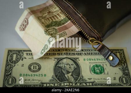 1 american dollar banknote and 100 russian rubles note in a wallet on the table. Stock Photo