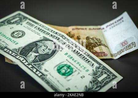 1 american dollar banknote and 100 russian rubles note on the table. Stock Photo