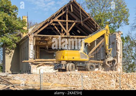An excavator stands on the rubble mountain during demolition work Stock Photo