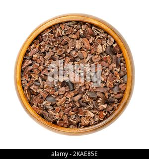 Cocoa nibs in a wooden bowl. Pieces of dried fermented kernels of cocoa beans, seeds of Theobroma cacao, generally processed into chocolate. Stock Photo