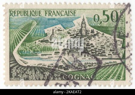 FRANCE - 1961 October 9: An 50 centimes green, prussian blue and slate postage stamp depicting View of Cognac is a commune in the Charente department, southwestern France. Administratively, the commune of Cognac is a subprefecture of the Charente department. The town gives its name to one of the world's best-known types of brandy or eau de vie. Drinks must be made in certain areas around the town of Cognac and must be made according to strictly defined regulations to be granted the name Cognac. Cognac is a unique spirit in that it is double-distilled Stock Photo