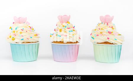 Buttercream cupcakes decorated with colorful and golden sprinkles isolated on white background. A set of festive vanilla cupcakes with waffle flowers Stock Photo