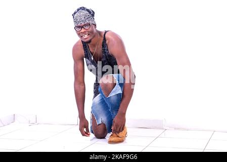 a young casual man standing on white background wearing bandanna on his knee is looking at the camera smiling Stock Photo