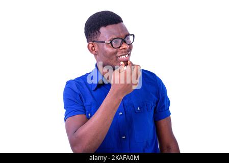 pensive young man wearing optical glasses, and looking sideways with raised hand on chin while smiling. Stock Photo