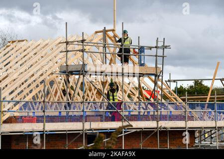 Pontypridd, Wales - October 2022: Construction workers working on the roof of houses being built on a new housing development by Bellway Homes Stock Photo