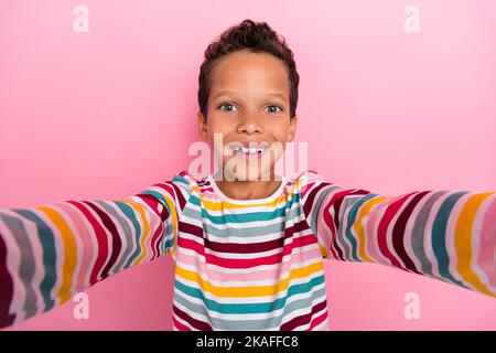 Portrait of nice adorable schoolboy wavy hairdo wear striped long sleeve doing selfie recording himself isolated on pink color background Stock Photo