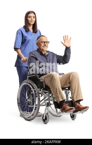 Female nurse standing behind a mature man waving and sitting in a wheelchair isolated on white background Stock Photo