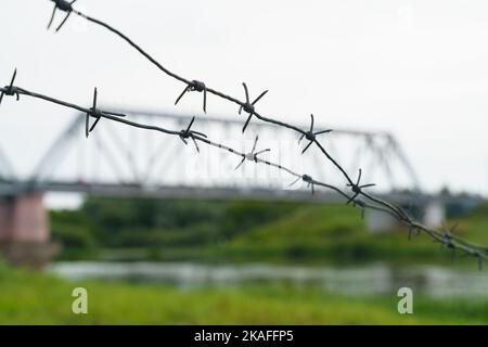 The concept of transport security. Barbed wire on the background of the railway bridge. Railway bridge in blur. Stock Photo