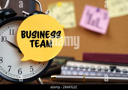 Business concept. The alarm clocks have a sticker with the inscription - Business team. There are office items in the background in a blurry backgroun Stock Photo