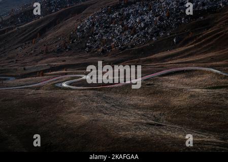 Traces of lights from cars driving on the winding road through the autumnal mountains at Passo di Giau at dusk, Dolomites, Italy Stock Photo