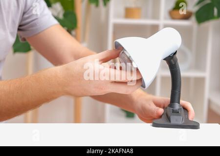 The man changes the lamp. Energy-saving lamp. Replacement of an energy-saving lamp. Stock Photo