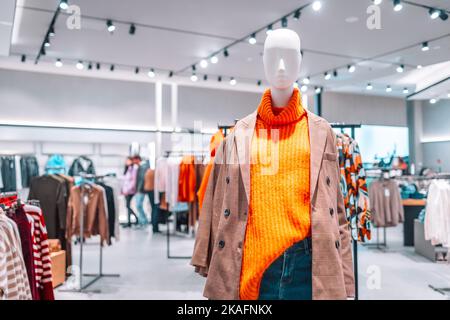 Mannequin dressed in a bright warm orange sweater, plaid jacket casual wear in a mall store. Female mannequins in a shop window. Stylish new Stock Photo