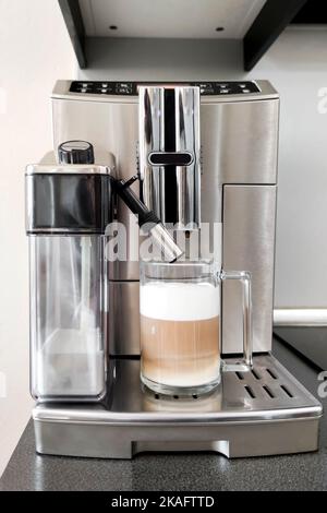 Cappuccino coffee in glass cup stands on stand of coffee machine, close-up Stock Photo