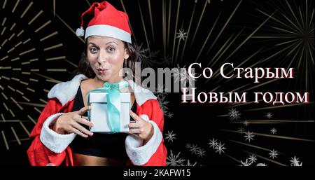 Portrait of young multiracial woman in santa hat holding present enjoying russian orthodox new year Stock Photo