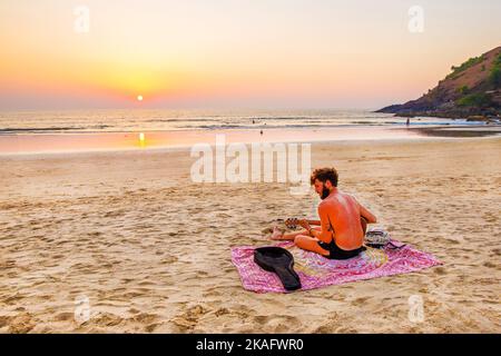 02-19-2019  Karnataka, Young man, musician, playing guitar on the beach in south India(Goa, Karnataka, Kerala) - amazing sunset Stock Photo