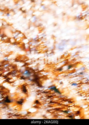Defocused light reflections of golden sparkling fabric. Blurred colorful bokeh background. Stock Photo