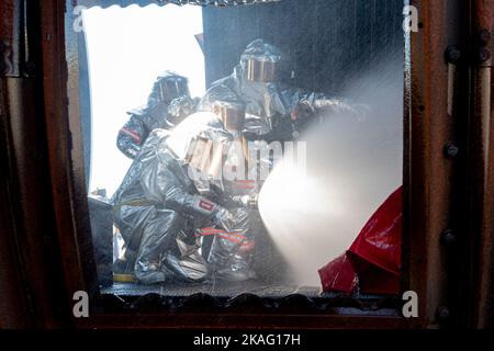 Japan Air Self-Defense Force firefighters spray water on an aircraft fire simulator during a bilateral training with the 374th Civil Engineer Squadron at Yokota Air Base, Japan, Oct. 26, 2022. Thirty-five JASDF members from six different bases gathered at Yokota AB to train and gain experience with 374 CES firefighters. (U.S. Air Force photo by Machiko Arita) Stock Photo