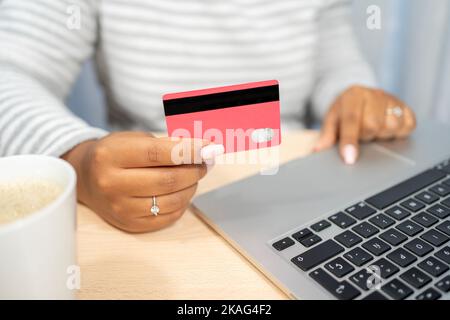 Close up African American woman shopping purchasing online, using laptop, typing, entering information, checking balance, browsing internet banking se Stock Photo