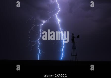 Lightning strikes behind a windmill in a strong thunderstorm near Springfield, Colorado Stock Photo